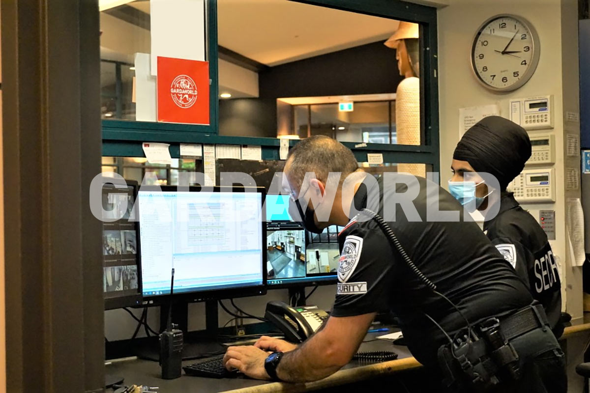 Agents de sécurité en uniforme avec masque regardant caméras de surveillances, mesures sanitaires COVID-19 (hommes)