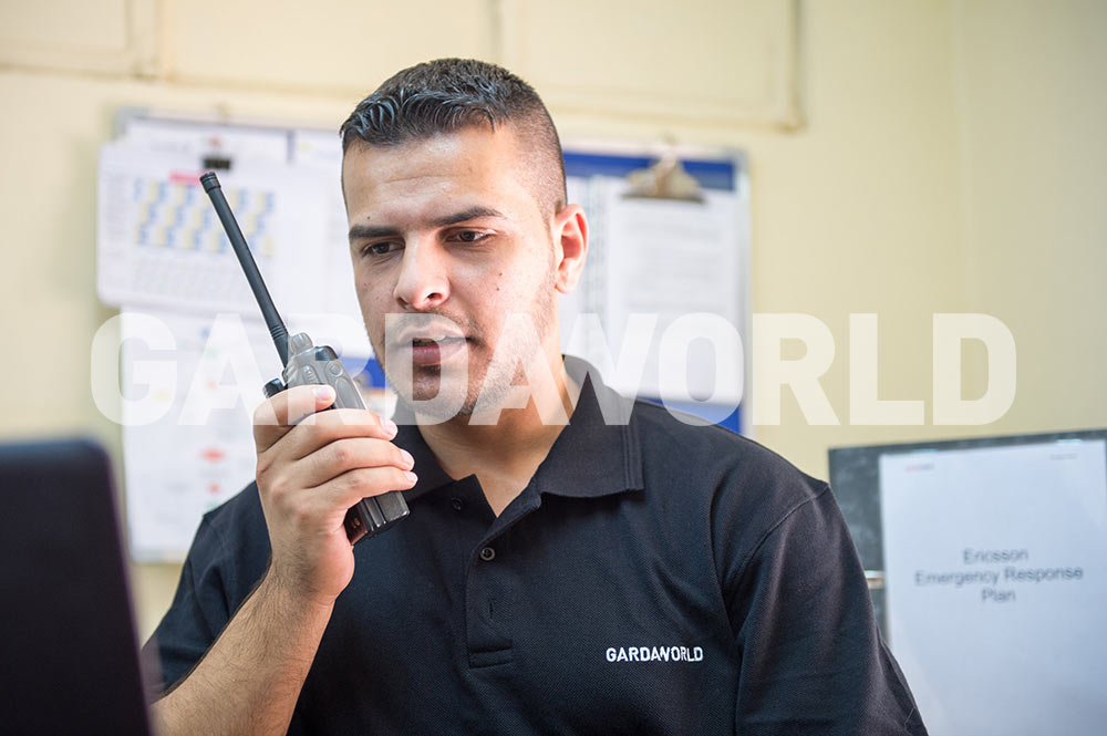 MEA Security Services, GardaWorld Agent with Walkie-Talkie Indoors. (man)