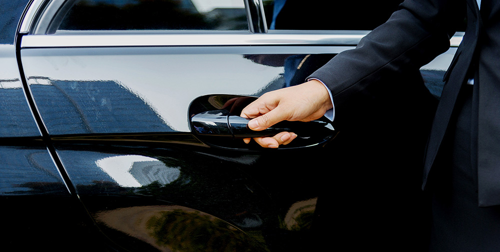 One of GardaWorld’s driver hire professionals opens black luxury SUV door