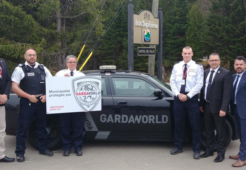 A team of GardaWorld professionals who support police in Lac-Supérieur, Quebec stand in front of a GardaWorld vehicle
