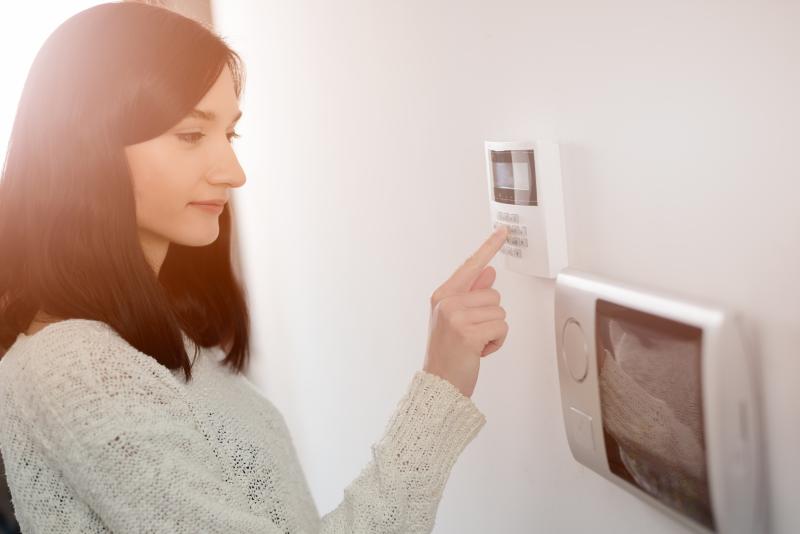 A woman enters a code on a security system keypad