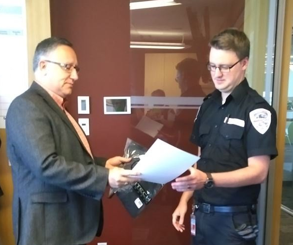 Jason Sangster, directeur de la sécurité des aéroports d'Edmonton, remet un certificat à l'agent de sécurité, Aaron Wray.