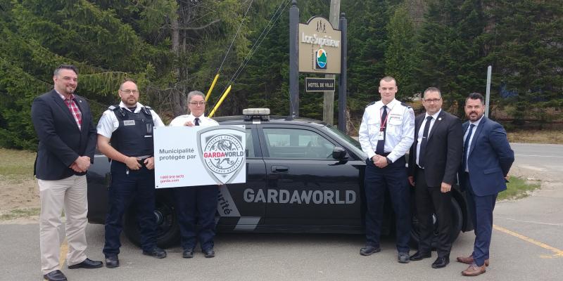 A team of GardaWorld professionals who support police in Lac-Supérieur, Quebec stand in front of a GardaWorld vehicle